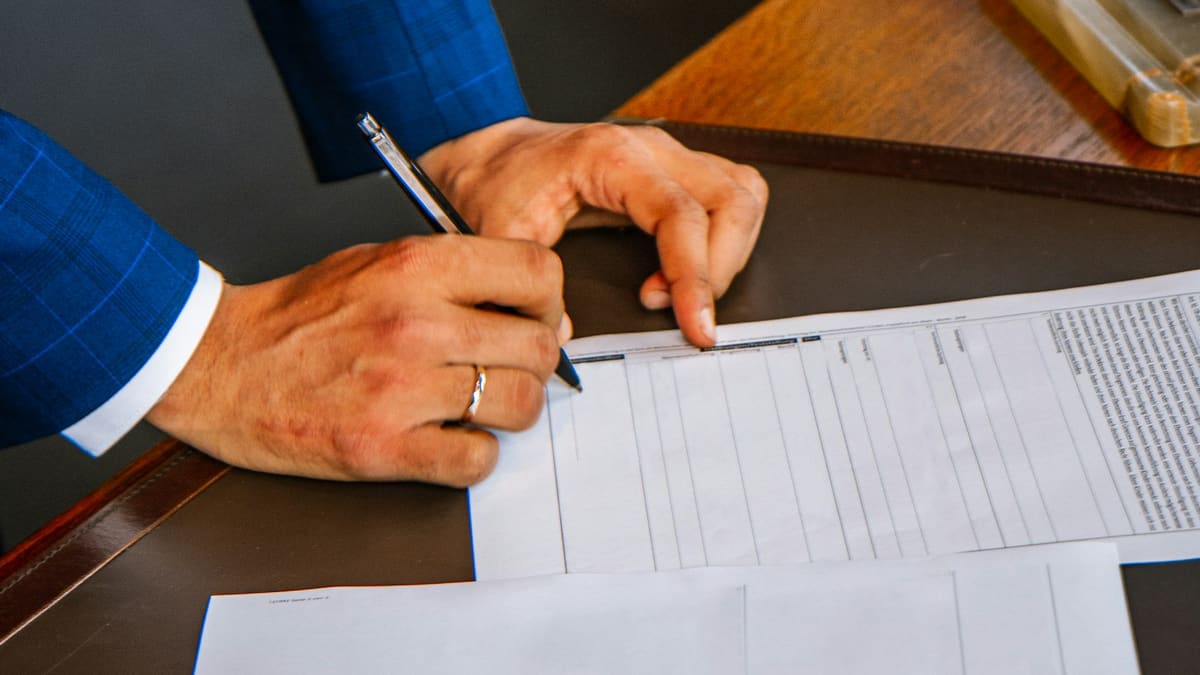 Hands filling in a contract with a pen